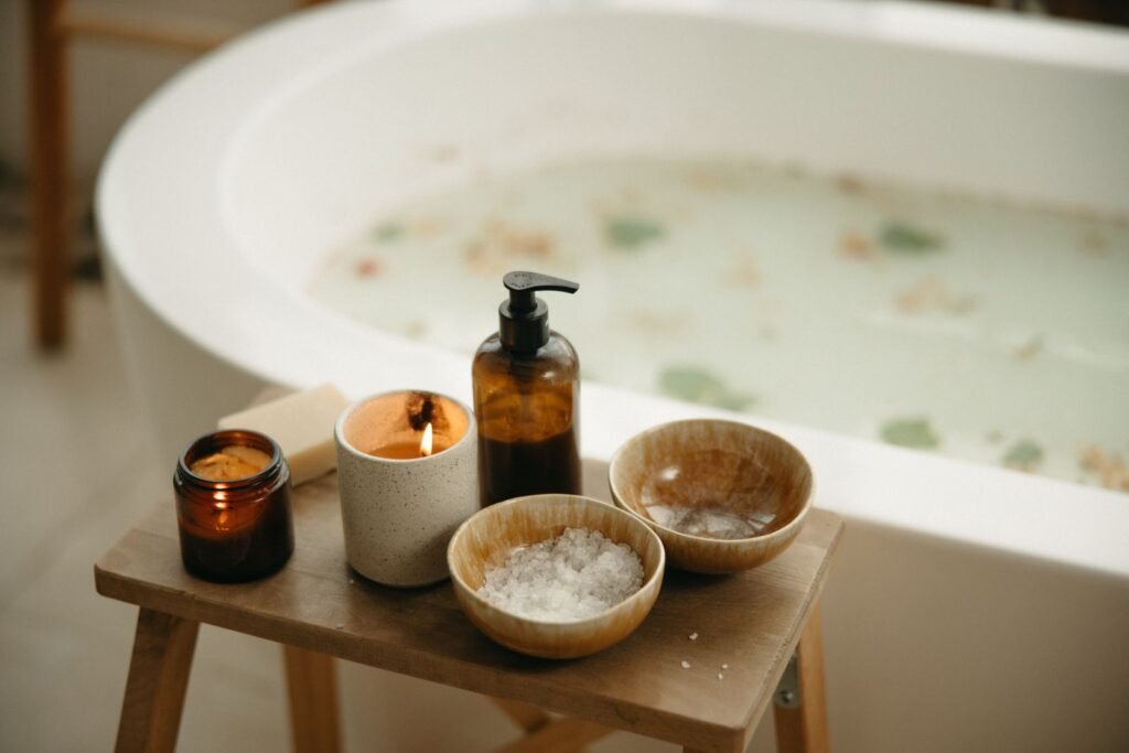 Freestanding bathtub with bath salts, a candle and body wash on a small wooden stool