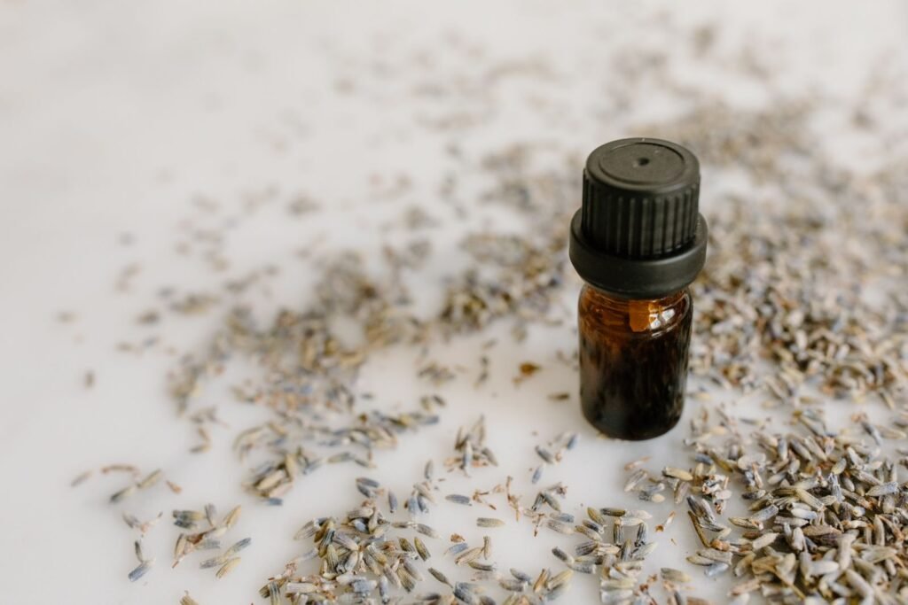 Small amber bottle of lavender essential oil surrounded by dried lavender buds