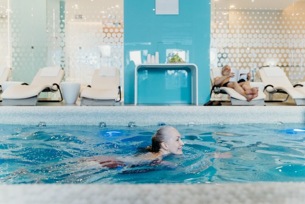 Woman swimming in a warm indoor spa pool with loungers in the background