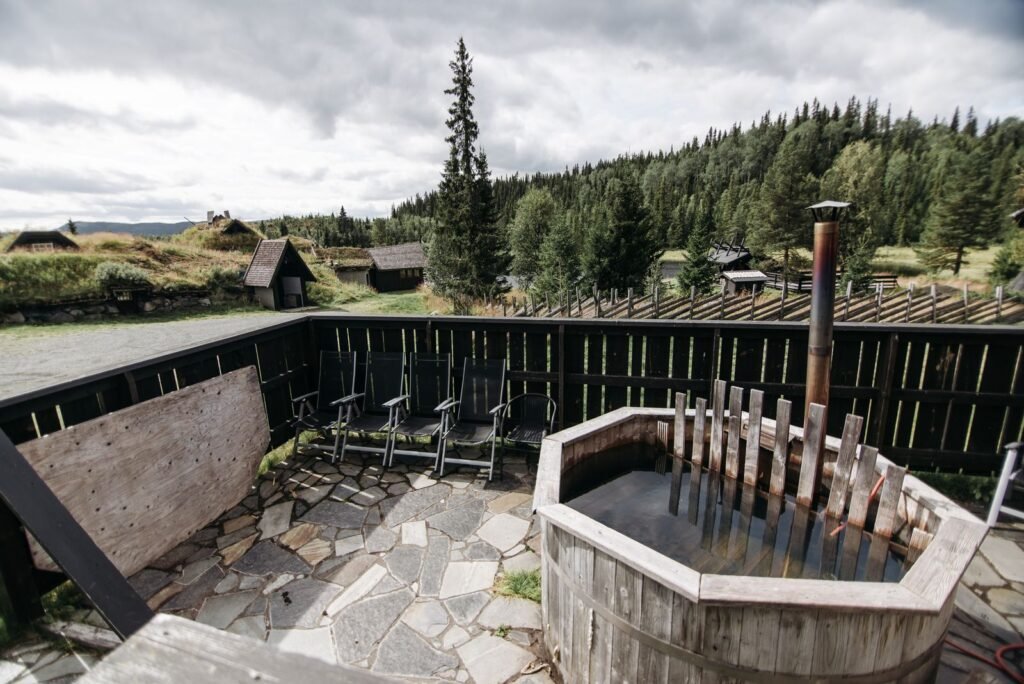 Wooden wood-fired hot tub on a stone deck with a view of forest and hills